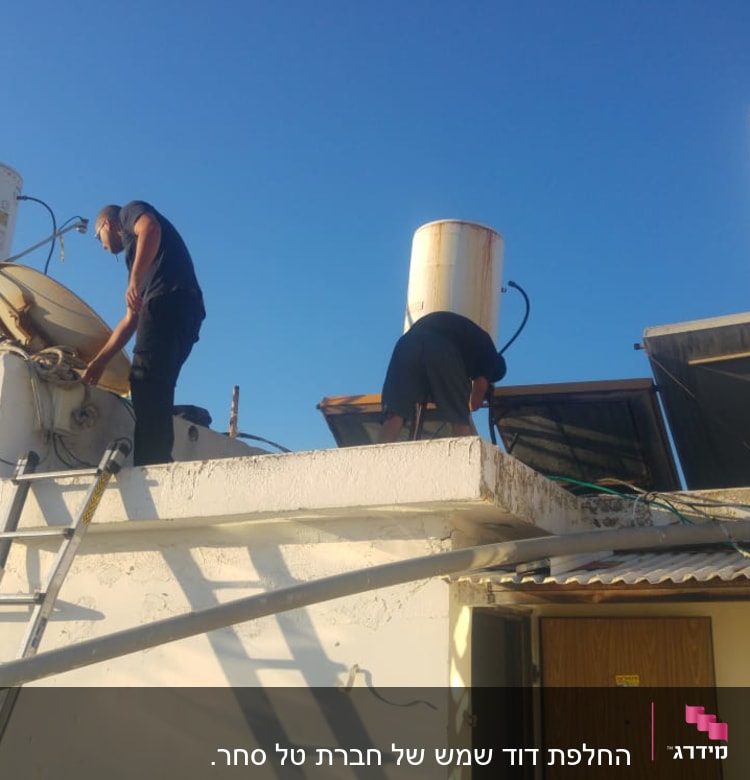 אנשים מתקנים דוד שמש על גג עם קולטים